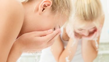 blonde hair woman washes her face with water