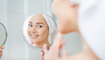 woman faces her face in the mirror smiling