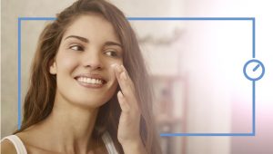 woman smiling applies cream on her face