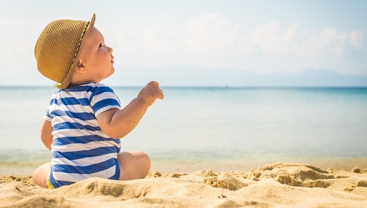 baby boy with hat playing in the sea