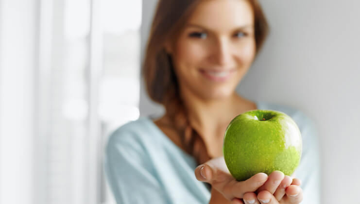 woman holds a green apple in her hands