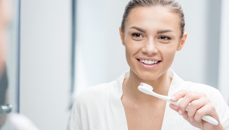 woman smiling and brushing her teeth