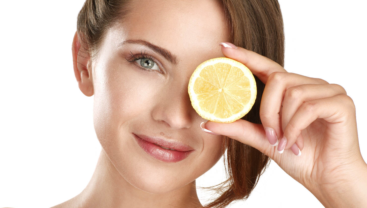 woman holding lemon slice in front of her eye
