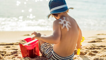 kid with sunscreen playing on the sand