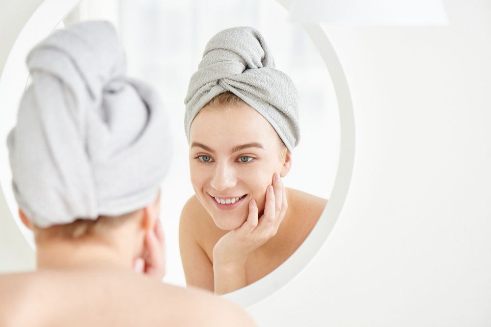 happy woman with towel on her head touches her face
