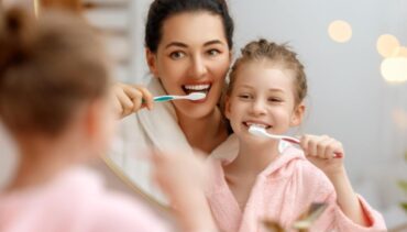 woman and little girl washing teeth