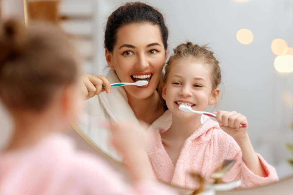 woman and little girl washing teeth