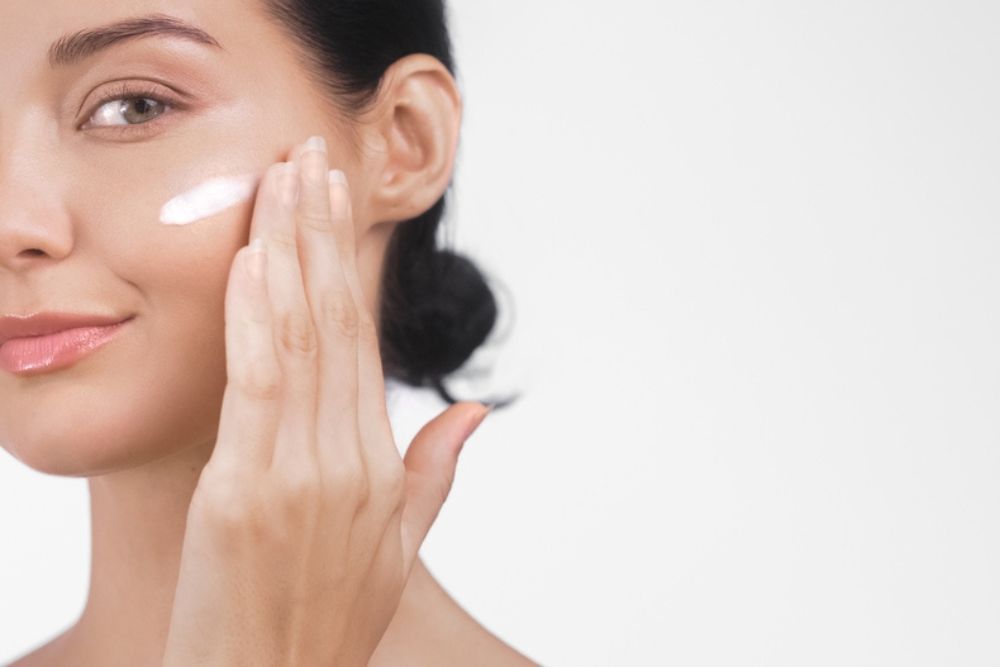 woman applies moisturizing cream in her face