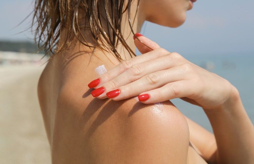 WOMAN APPLYING SUNSCREEN