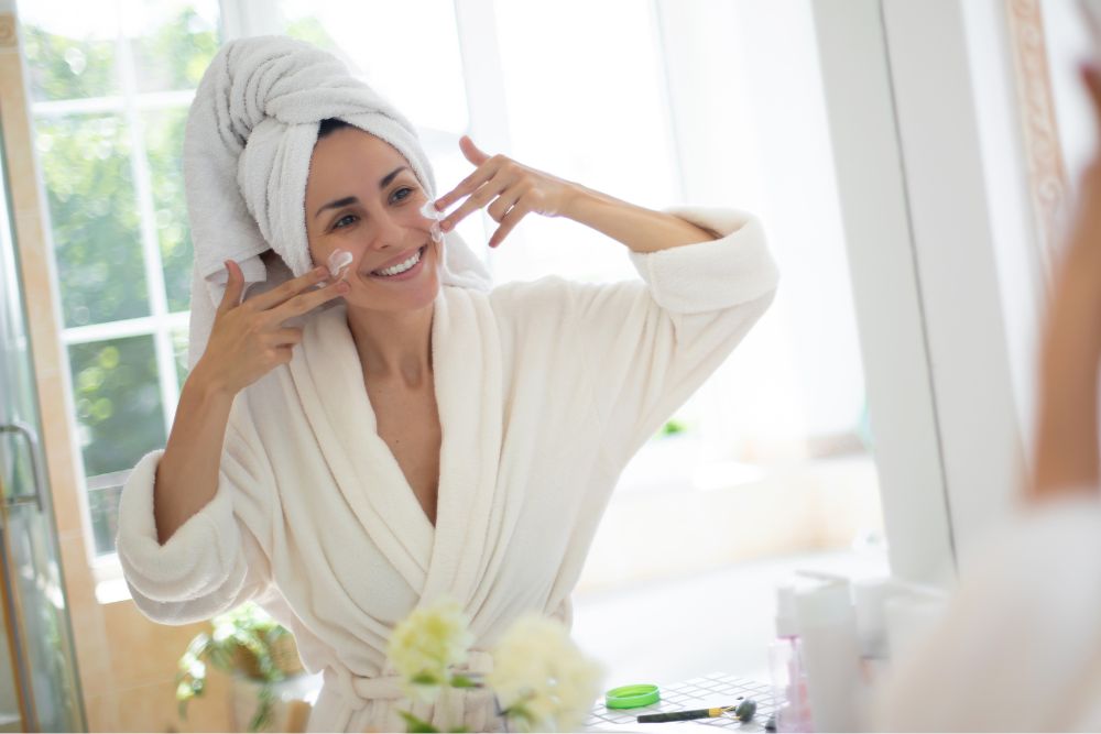 WOMAN APPLYING FACE CREAM