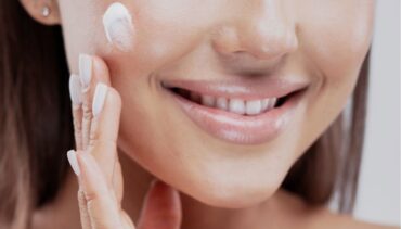 WOMAN APPLYING CREAM ON HER FACE