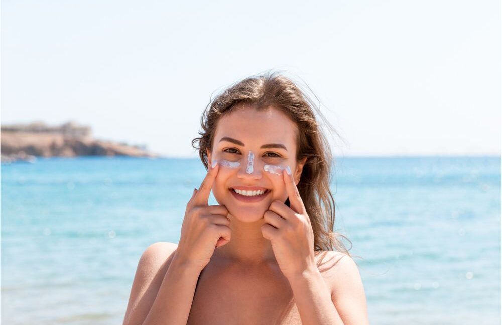 happy woman applying sunscreen on the beach