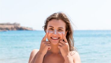 happy woman applying sunscreen on the beach