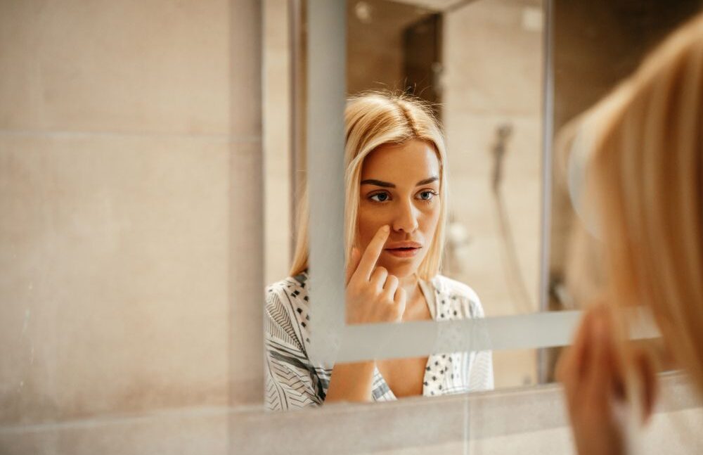 Attractive young woman standing in front of the mirror